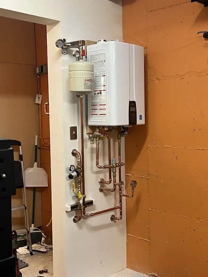 Plumbing technician inspecting water heater connections in Littleton